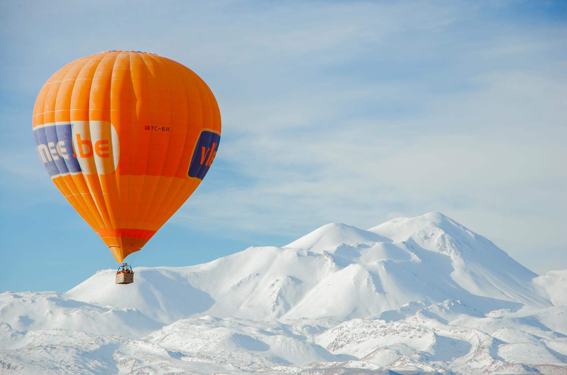 Pomarańczowy balon nad ośnieżonymi górami w słoneczny zimowy dzień