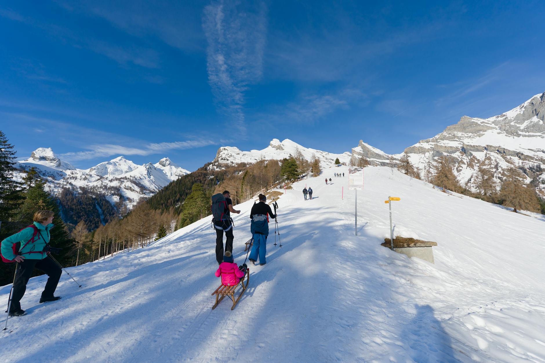 Turyści idący ośnieżonym szlakiem górskim w słoneczny dzień