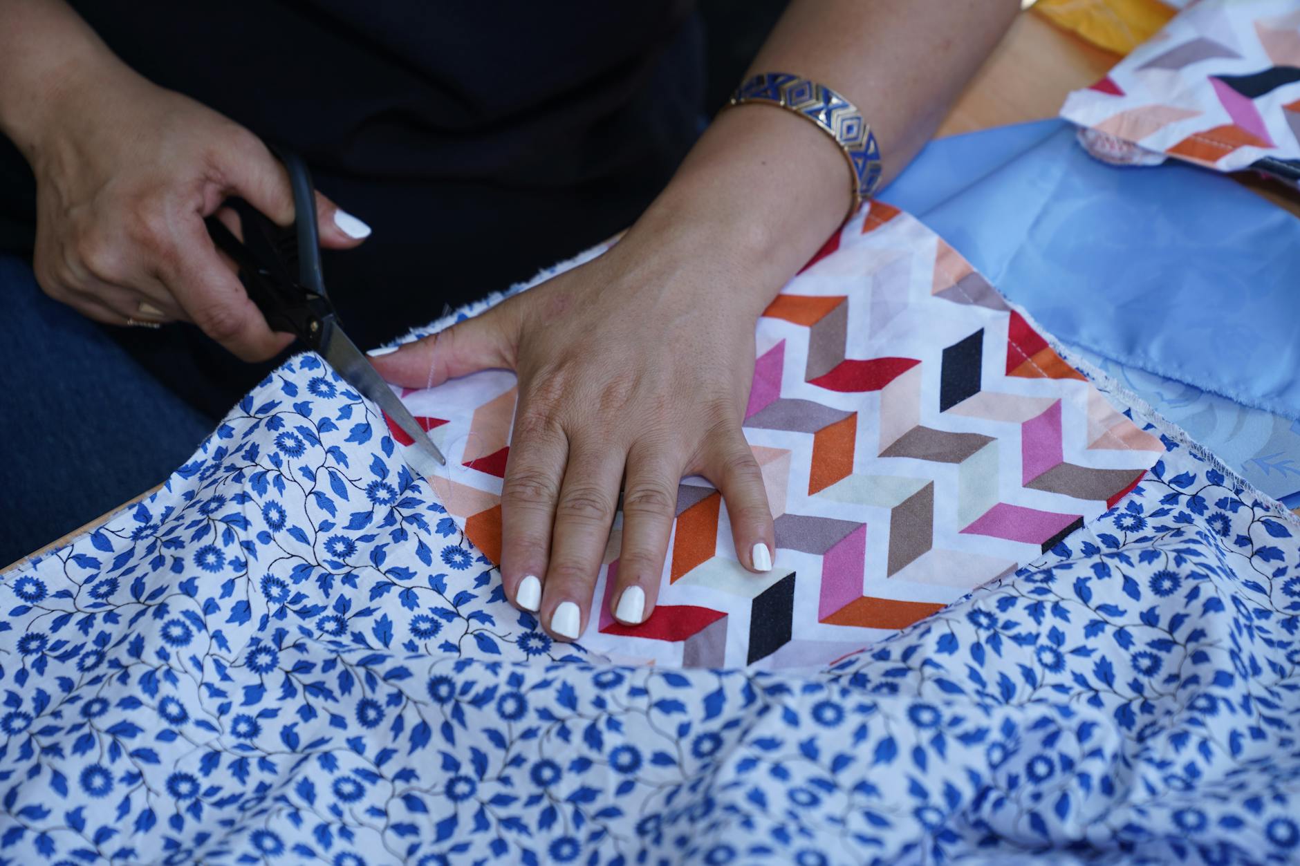 Dłonie wycinające kolorowe tkaniny nożyczkami do patchworku